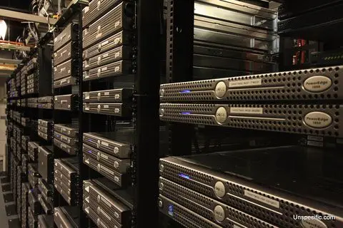 Long rows of server racks inside a large data center with blue indicator lights