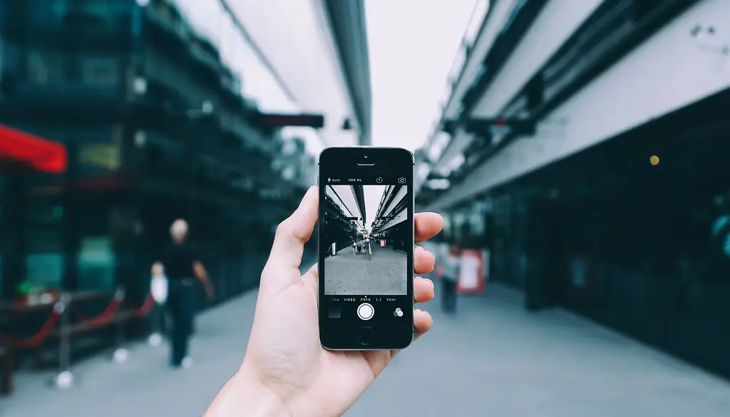 A person holding an iPhone while walking on a busy street