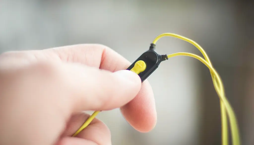 A person listening with wired over-ear headphones connected to a phone